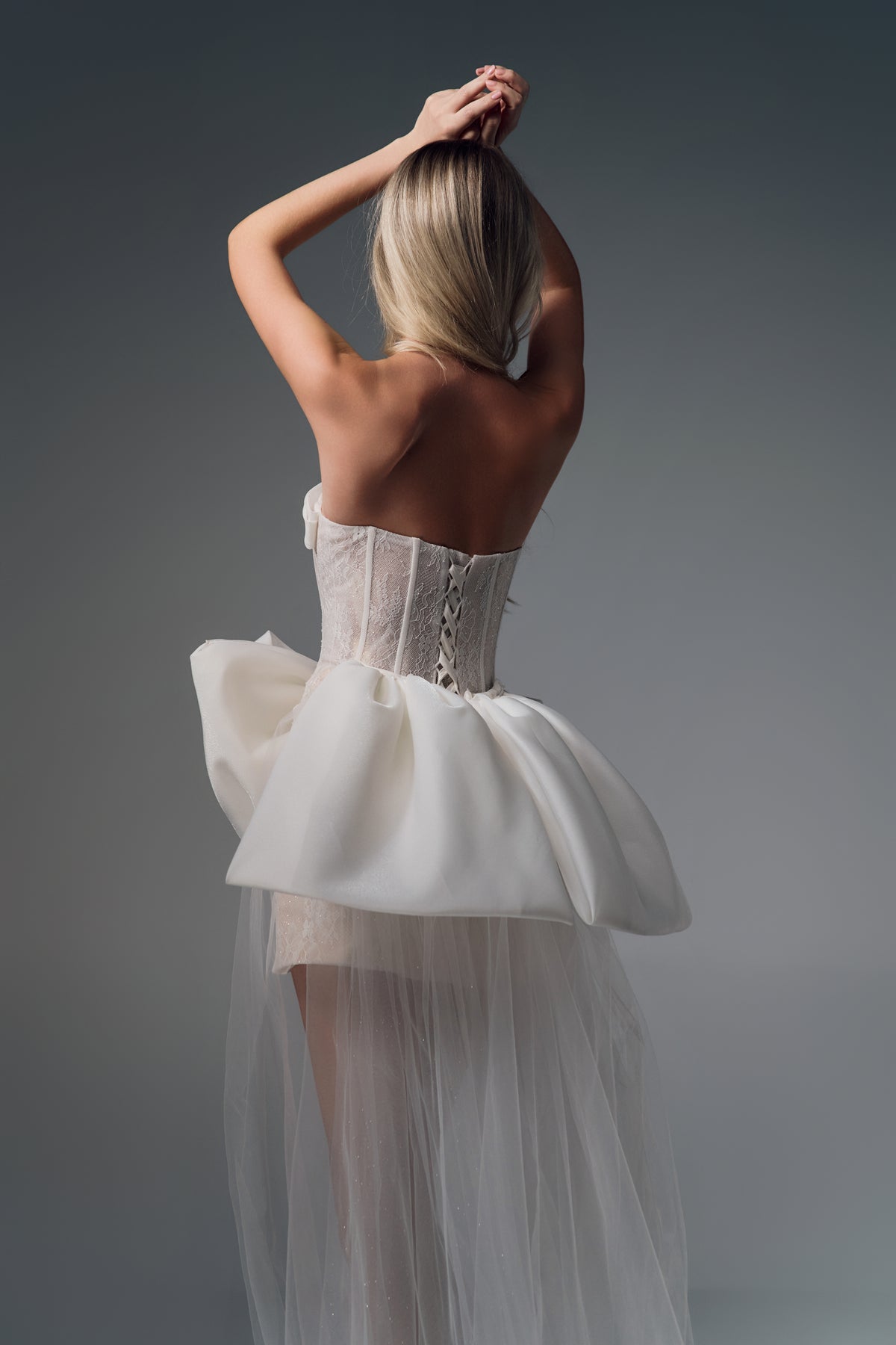Novella sheer-bodice mini wedding dress with bow train, back view